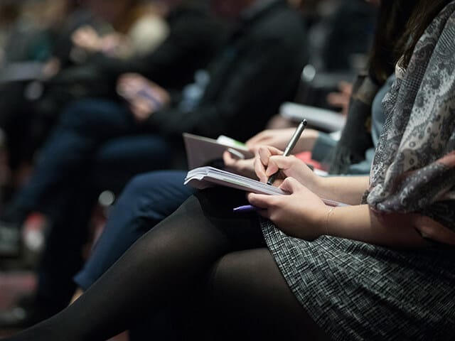 prepare-for-event 1.49.19 PM A woman taking notes at a trade show event.